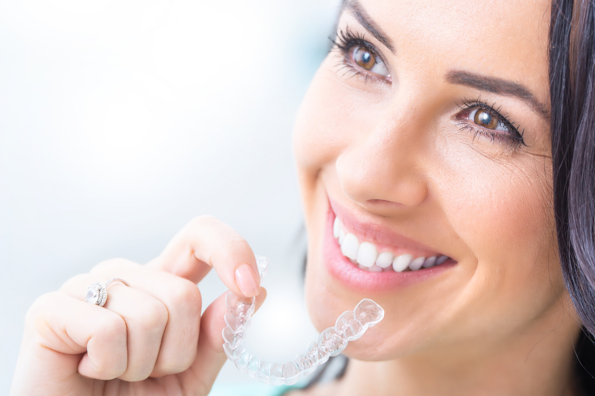 Paciente sonriendo mientras sostiene un alineador transparente para su tratamiento de ortodoncia invisible en Cuautitlán Izcalli.